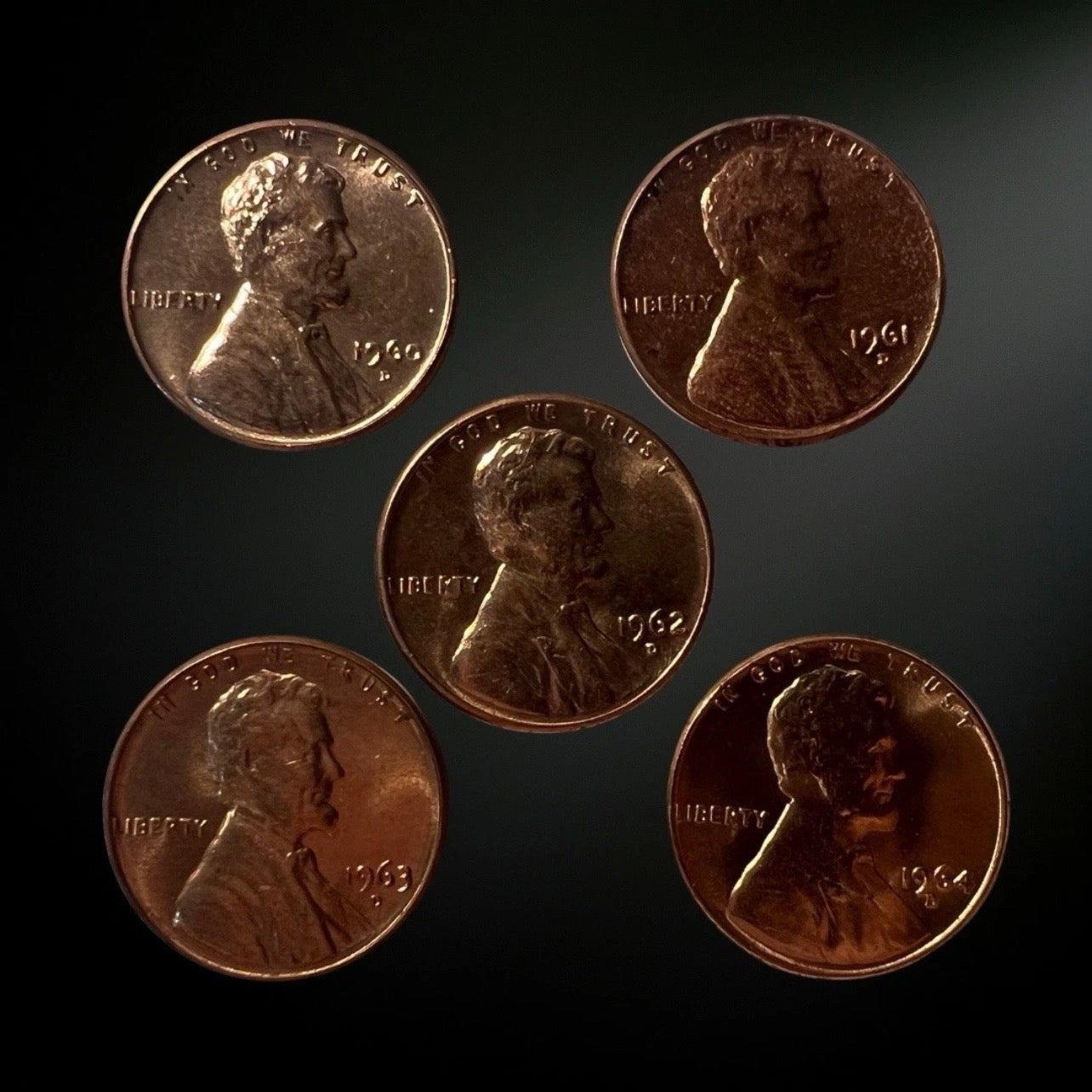 Five pennies with different dates arranged on a dark background